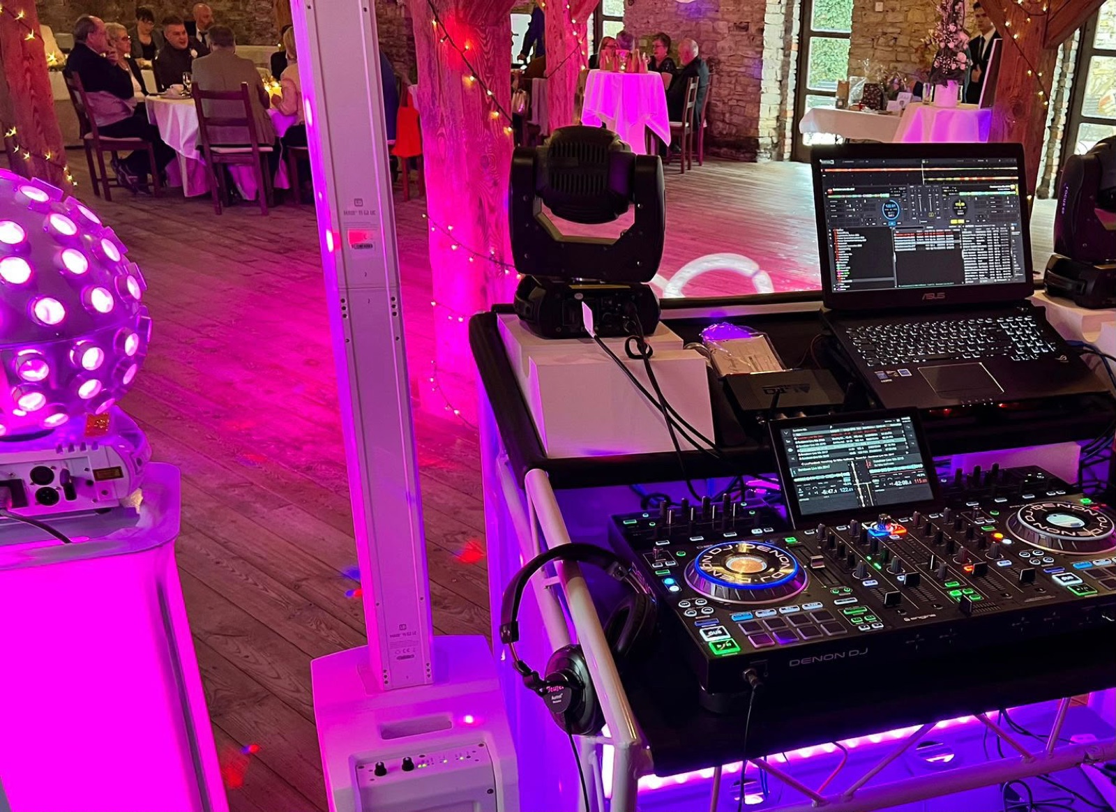 DJ-Pult mit Controller, Laptop und Lichtkugel, im Hintergrund die Hochzeitsgesellschaft